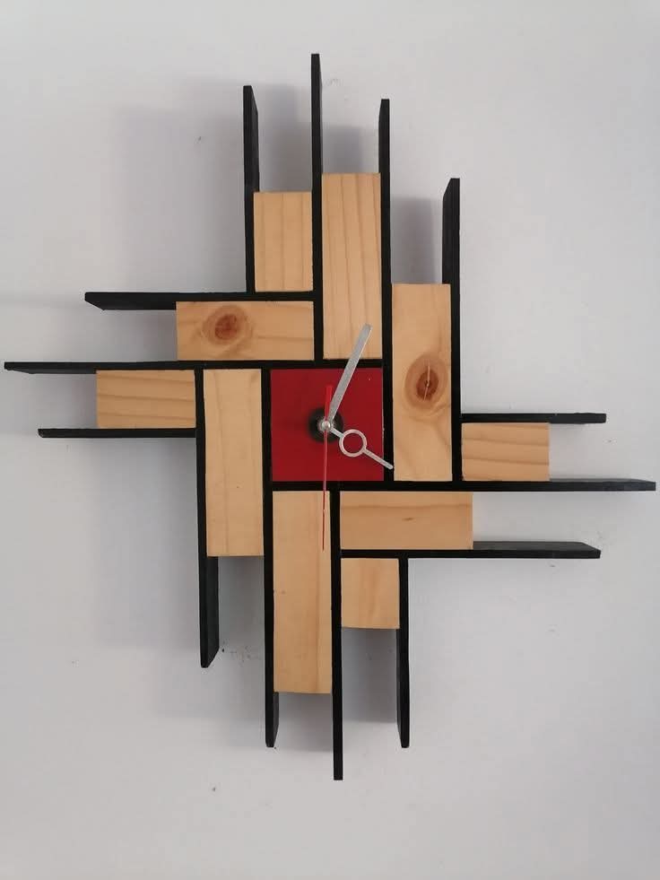 Reloj de pared con estructura geométrica de perfiles de acero negro y bloques de madera natural, con centro circular rojo y manecillas plateadas